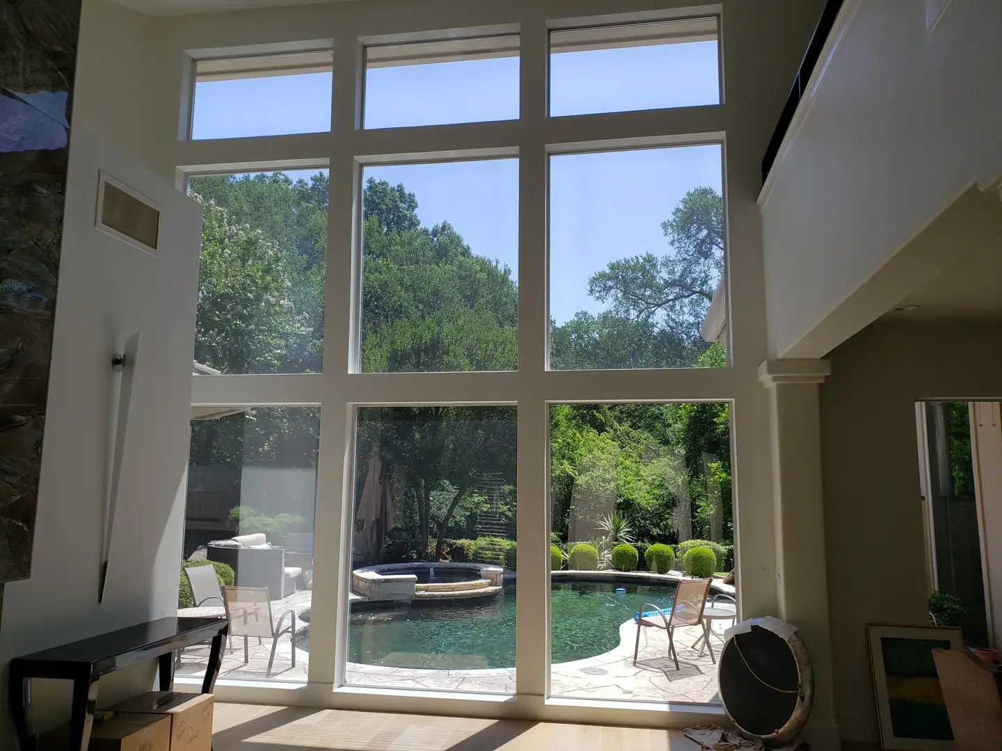 Two-story great room nine-pane floor-to-ceiling window wall pool view solar film DFW