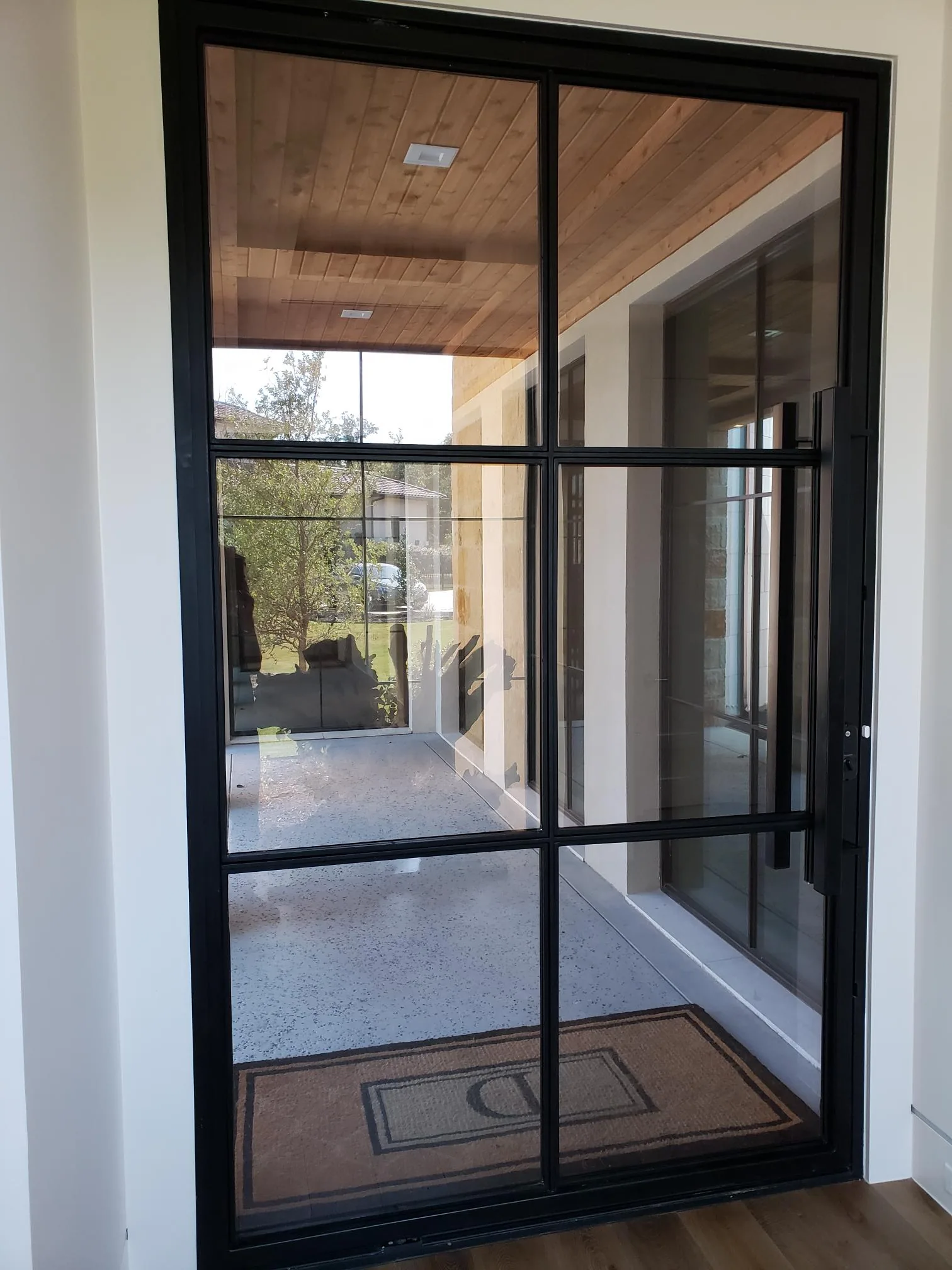 Modern home black steel-frame glass entry door cedar porch ceiling solar film DFW