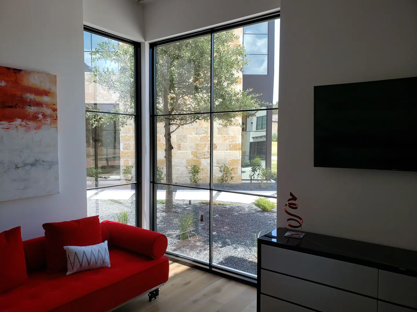 Modern home corner floor-to-ceiling steel frame windows red sofa courtyard view