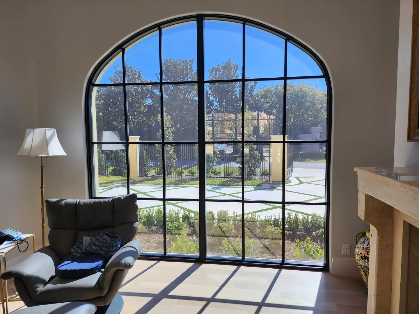 Luxury home easy chair lamp large arched window crisscross driveway view